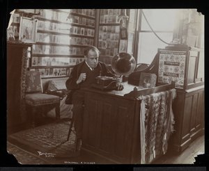Marshall P. Wilder luistert naar een plaat op een victrola in zijn kantoor